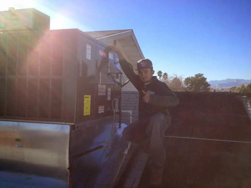 HVAC technician performing AC Tune-Up on a rooftop unit in Lochbuie